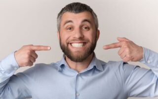 Happy man pointing to his clean white teeth after AirFlow dental cleaning on Long Island, NY